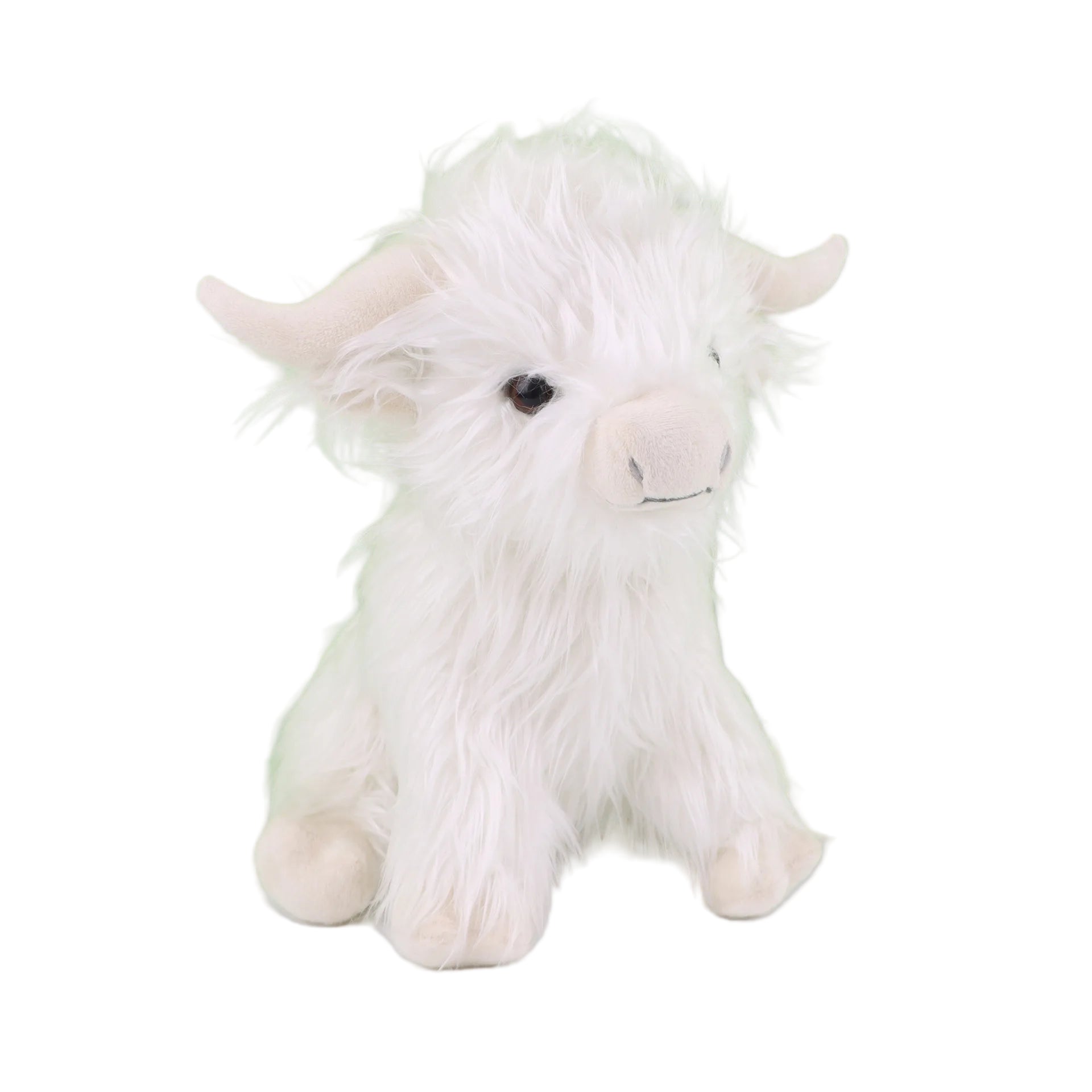 White plush toy cow on a white surface with a green background